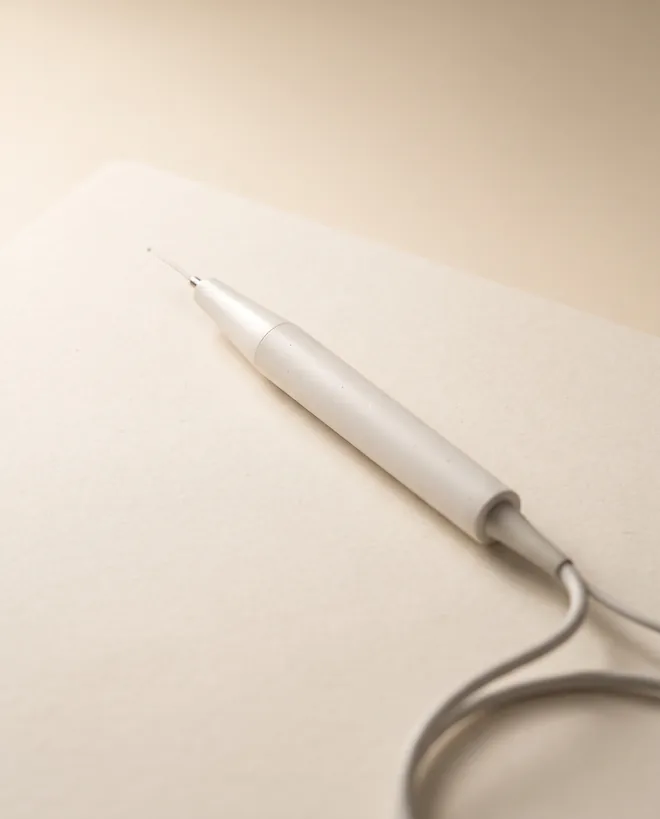 A slim white dental laser handpiece with a fine fibre tip
