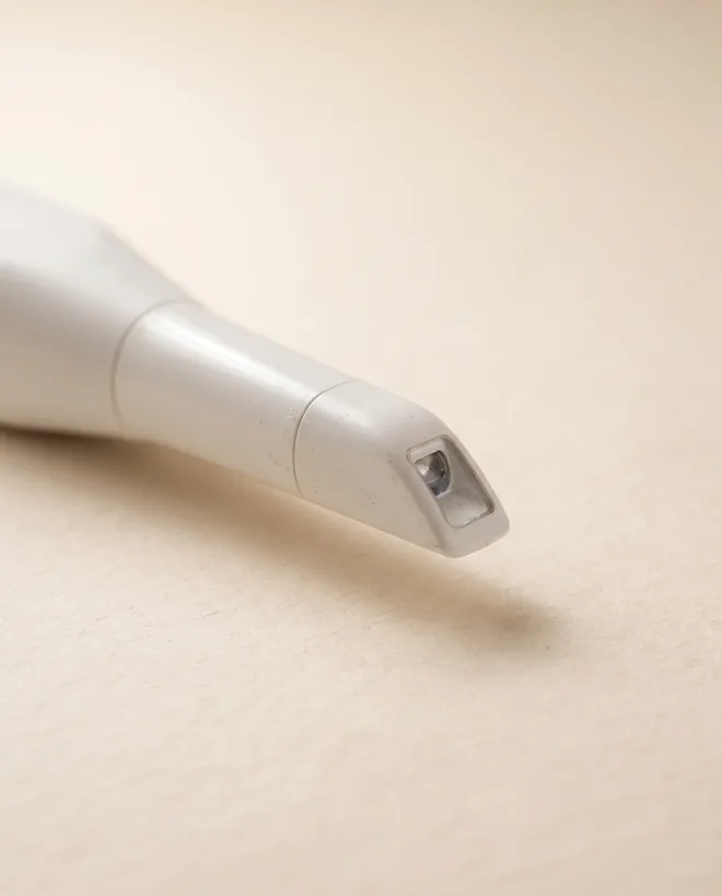 The slim white wand tip of an intraoral dental scanner