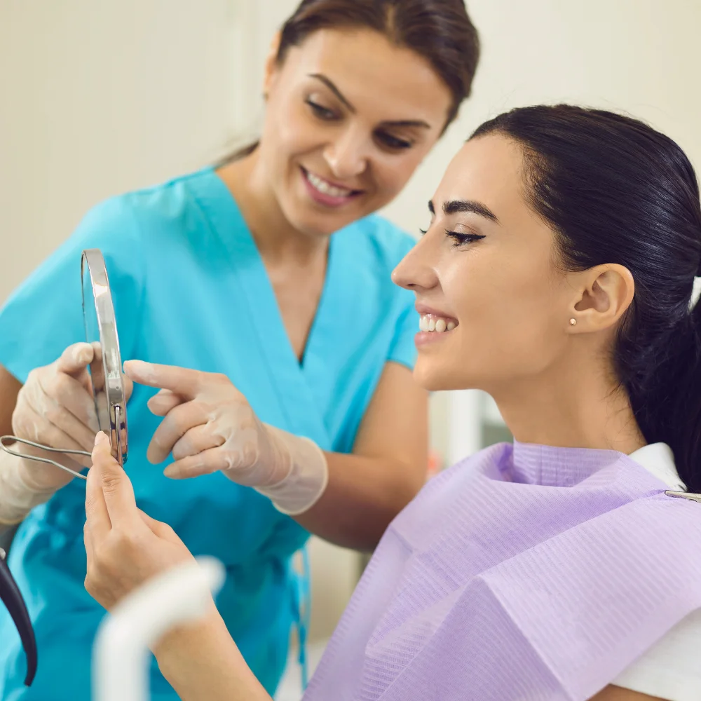 Female patient smiling while reviewing oral surgery results with a dental professional
