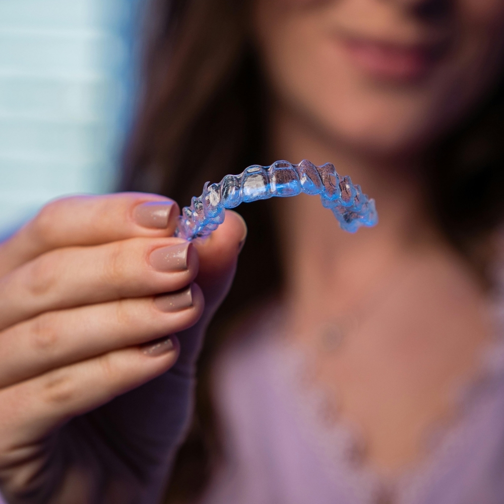 Close-up of a person holding custom clear aligners used for discreet orthodontic teeth straightening treatment