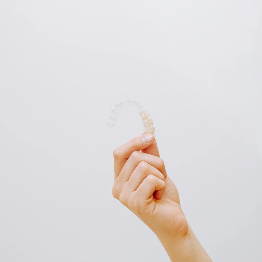 Hand displaying a clear aligner tray used to gradually straighten teeth without traditional braces