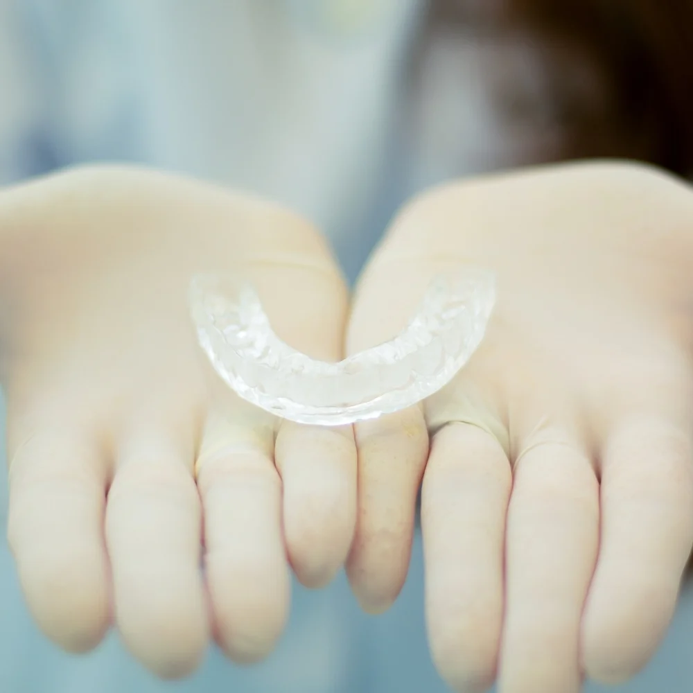 Transparent dental aligner resting on hands for comfortable orthodontic treatment and smile improvement